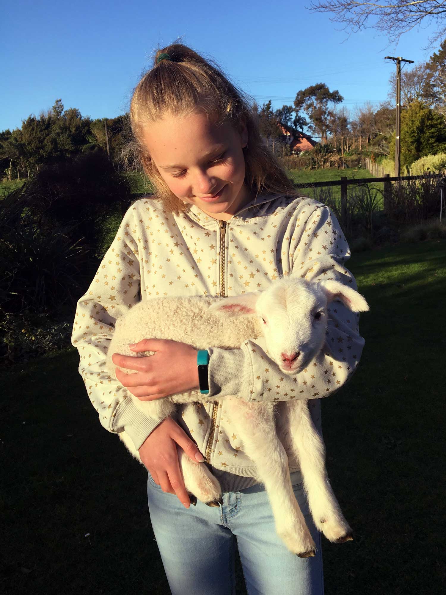 A lamb is held lovingly by a young lady who is smiling.